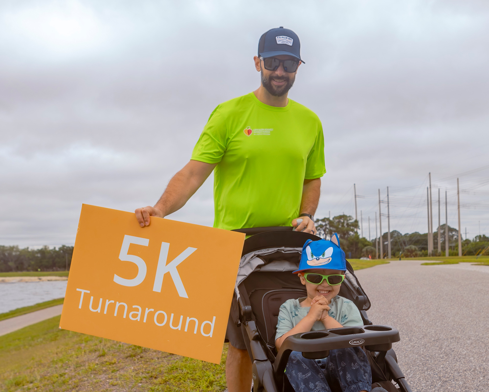 A man holding a sign next to a stroller.