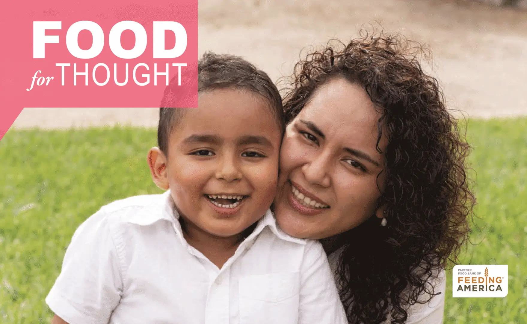Mother and child smiling on grass.